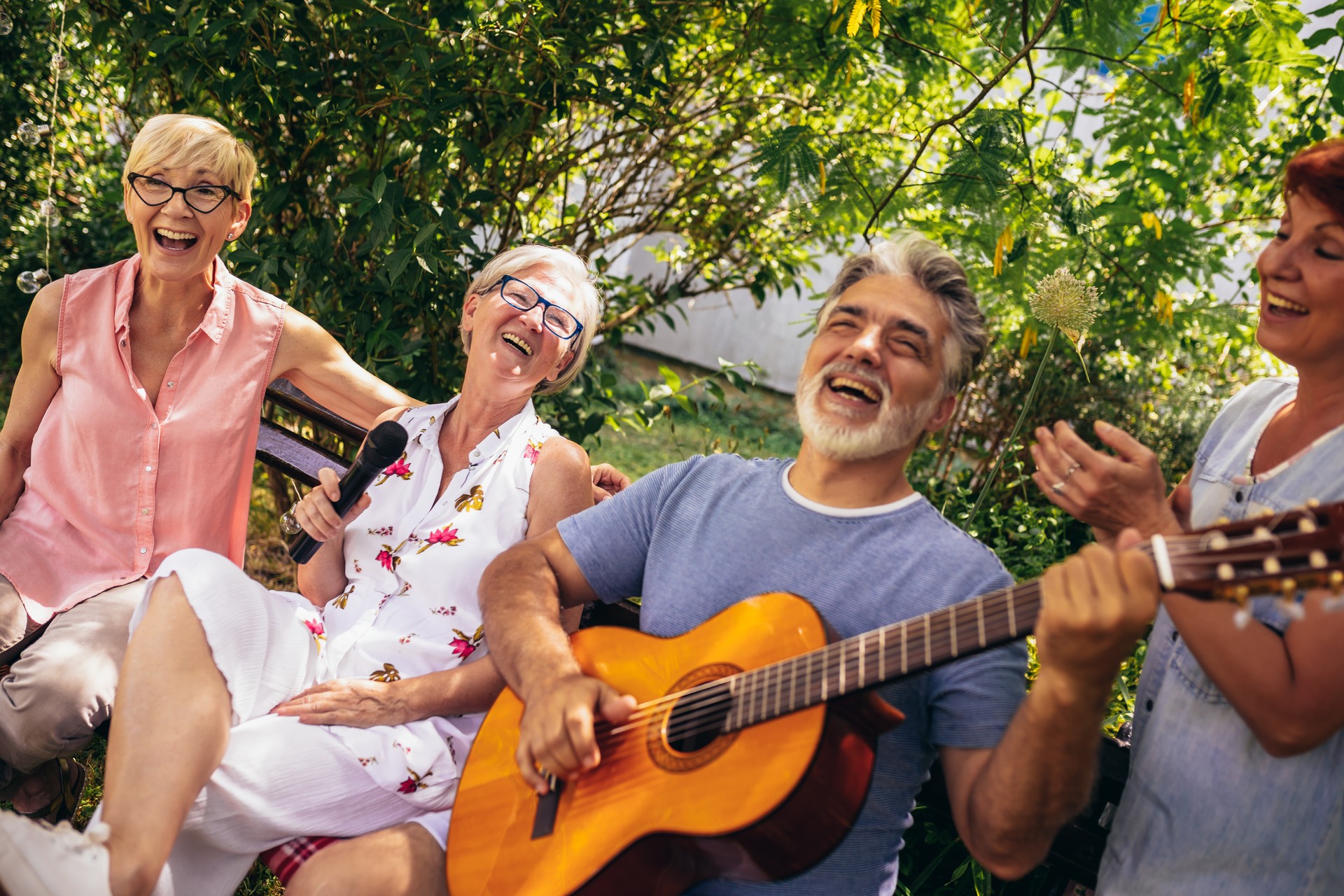 Group of elderly people enjoying their retirement by going on a picnic, playing a guitar and singing.