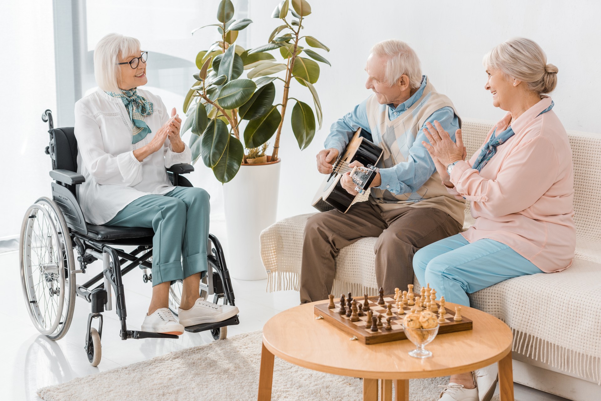 senior homme assis sur le canapé et jouer de la guitare acoustique pour les femmes