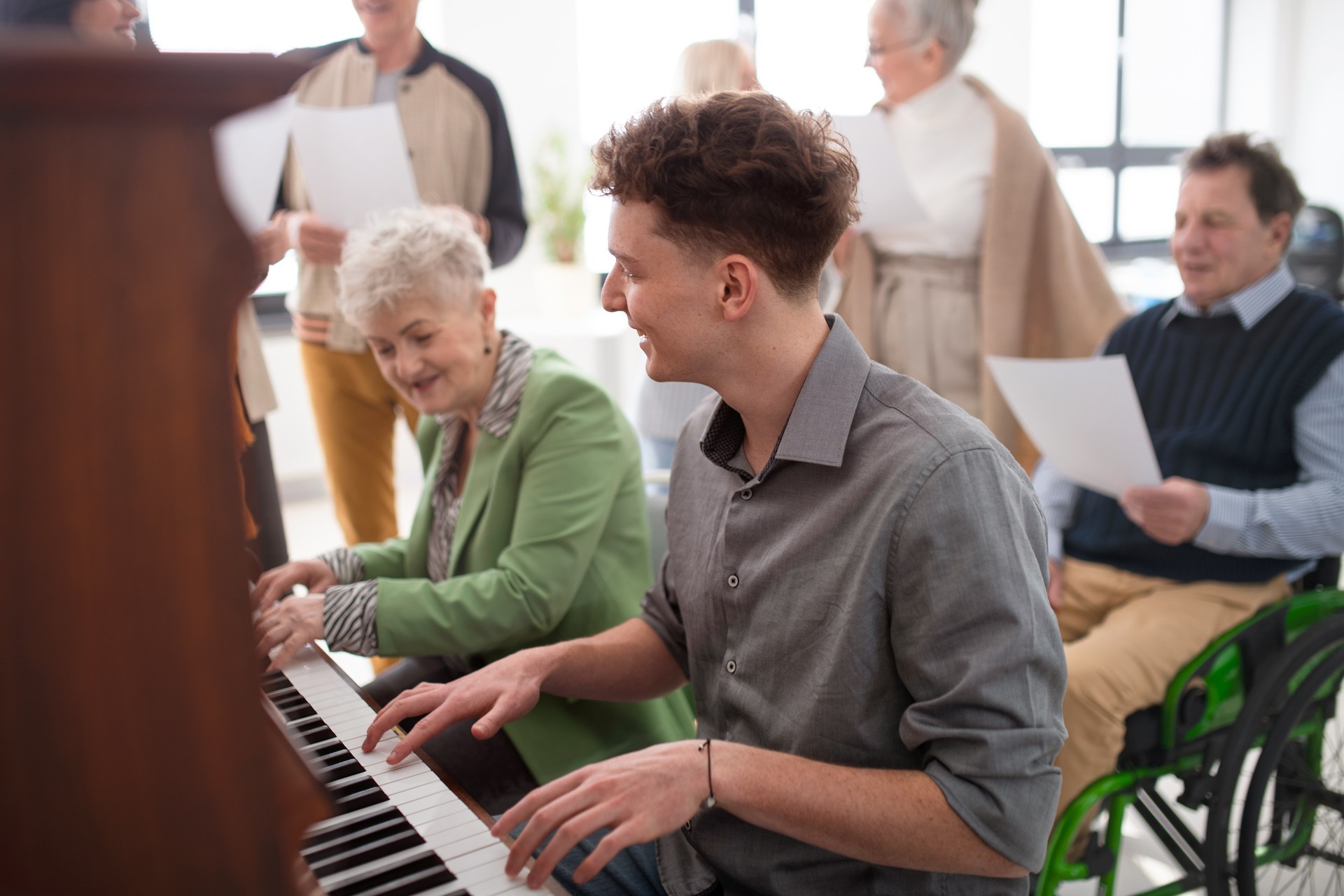 Femme âgée avec un jeune professeur jouant au piano lors de la répétition de la chorale.